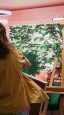 Kırsal bir atölyede ressam, rengarenk bir başyapıt yaratmak için bir palette çeşitli suluboya boyaları karıştırır. Fırçayla resim yapan ve beceri ve sanat eseri sergileyen bir kadın.