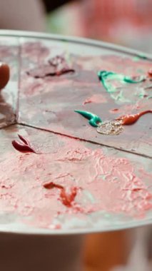 Bir sanat stüdyosunda, ressam bir palette birden fazla suluboya boya boya ile resim yapar. Yetenekli adam resimlerinde aletler ve hayal gücü, sanatsal yaratıcılık. Kapat.