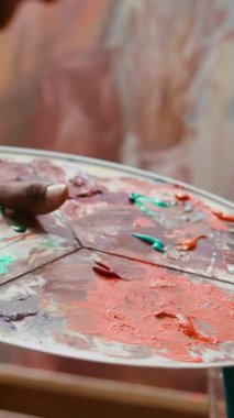 Bir sanat stüdyosunda, ressam bir palette birden fazla suluboya boya boya ile resim yapar. Yetenekli adam resimlerinde aletler ve hayal gücü, sanatsal yaratıcılık. Kapat.