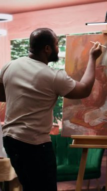 Bir sanat stüdyosunda, sanatçı bir palette çeşitli suluboya boyalar karıştırır ve tuvalde kırsal bir başyapıt yaratır. İnsan aletlerle resim yapar ve yeteneğini gösterir, sanat eserleri yaratır.