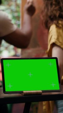 Dikey Video Çeşitliliği sanatçıları, güzel sanat galerisi sergisi için başyapıt üzerinde işbirliği yaparak, izole edilmiş maket ekranın yanına yeni sanat eserleri çiziyorlar. Ressam ve çırak suluboya boya boya kullanıyor.