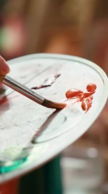 Bir sanat stüdyosunda, sanatçı bir palette suluboya boya boya karıştırır ve tuvalde kırsal bir başyapıt yaratır. Aletlerle resim yapan ve yeteneğini, sanat eserlerini gösteren bir kadın. Kapat.