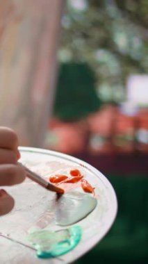 Bir sanat stüdyosunda, sanatçı bir palette suluboya boya boya karıştırır ve tuvalde kırsal bir başyapıt yaratır. Aletlerle resim yapan ve yeteneğini, sanat eserlerini gösteren bir kadın. Kapat.