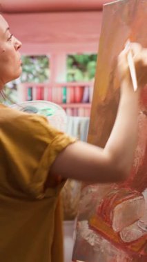 Dikey Video Ressamı, resim atölyesinde, renkleri fırçayla harmanlayarak bir tuval üzerinde bir başyapıt yaratmak için yeteneğini ve kravat boyasını kullanır. Özel bir resim tekniğiyle kırsal bir sanat eseri.