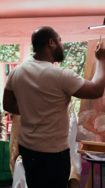 Dikey Video Sanatçısı, sanat galerisi sergisi için yaratıcı süreci boyunca belli bir resim tekniği kullanarak yeni başyapıtı üzerinde çalışıyor. Tuval üzerinde güzel bir eser. Kamera B.