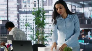 Memnuniyetsiz Hintli işçi işini kaybediyor ve eşyalarını bir kutuda topluyor, çalışma yerini terk ediyor ve işsizlik konusunda sıkıntılı hissediyor. Kadın kovuluyor, kovuluyor. Kamera A.