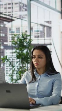 Dikey görüntülü Hintli iş kadını iş tahminlerini ve ofis masasındaki planlarını inceliyor, strateji planlaması yapıyor. Veri analisti şirketin amaçlarına ve kaynak tahsisine odaklanıyor. Kamera B