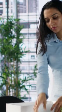 Dikey video hoşnutsuz Hintli işçi işini kaybediyor ve eşyalarını bir kutuda topluyor, çalışma yerini terk ediyor ve işsizlik konusunda endişeli hissediyor. Kadın kovuluyor, kovuluyor. Kamera.