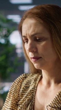 Dikey video. Yorgun iş kadını masasında yorgunluk belirtileri gösteriyor. İşinin talepleri karşısında bunalmış. İşçi profesyonel zorluklarla ve duygusal zorluklarla mücadele ediyor, zor bir gün.