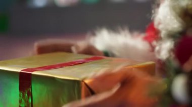 Aziz Nicholas, kır evindeki kurdele ve fiyonklarla birçok hediyeyi süslüyor. Kırmızı elbiseli Noel Baba Kuzey Kutbu 'nda Noel hediyeleri için renkli ambalaj kağıdı kullanır. Kamera A.