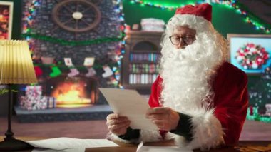 Noel Baba 'nın portresi çocuklardan gelen mektupları okuduktan sonra iyi çocukların listesini sunduktan sonra baş parmağını gösteriyor. Aziz Nicholas kış mevsiminde hediye teslimatına hazırlanıyor. Kamera B.