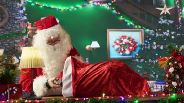 Beyaz sakallı yaşlı bir adam hediye dolu çuvalını bağlıyor ve dünya turuna hazırlanıyor. Kış tatili ruhunu yaymak ve çocukları şaşırtmak, x mas geleneği. Kamera A.