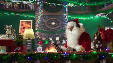 Mutlu Noel Baba akıllı telefonunda Noel şarkıları ve neşeli müzikler dinliyor. Takım elbiseli beyaz sakallı adam bayram neşesini odunlukta dağıtıyor. Aziz Nicholas kulaklık kullanıyor. Kamera B.
