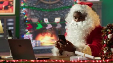 Noel Baba gibi giyinmiş Afrikalı bir Amerikalı telefonda sohbet ediyor, Noel arifesindeki yolculuğa hazırlanıyor. Beyaz sakallı karakter oyuncaklar ve hediyeler getirir. Kamera A.