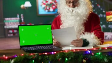 Noel Baba, kulübesinde, kroma anahtar ekranının yanında oturuyor. Kuzey Kutbu 'ndaki posta kutusundan gelen mektupları okuyor. Noel Baba Aralık tatili neşesini yayıyor, beyaz sakallı adam. Kamera A.