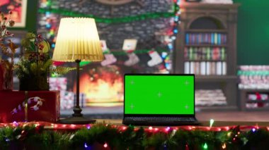 Laptop 'ta yeşil ekranlı, renkli süslemeler ve çelenklerle Noel tatili sezonu için büyülü bir ortam yaratan şenlikli boş ahşap bir kulübe. Geleneksel bayram.