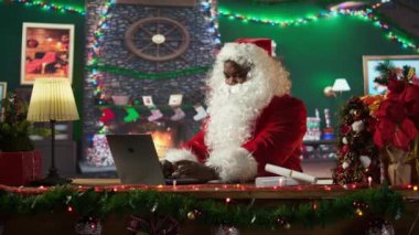 Noel Baba hediye takibi için internet sayfalarında gezinen şenlikli kütük kulübesinde bir laptop kullanıyor. Kuzey Kutbu Noel büyüsüyle dolu. Aziz Nicholas dijital çağı kucaklıyor. Kamera B.