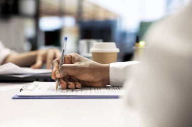 Job interview candidate filling paperwork after agreeing terms with human resources worker. Close up shot of applicant signing contract with HR employee after being selected to work for company clipart