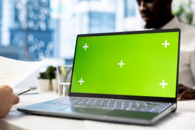 İnsan kaynakları uzmanı yeşil ekran dizüstü bilgisayarı üzerinde çalışıyor, işe başlamak için doğru adayları belirliyor, aday niteliklerini belirlemek için özgeçmişleri gözden geçiriyor. Kelle avcısı model defterle tarama işlemi yapıyor