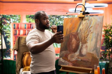 Genç ressam bir video kaydediyor ve şaheserini tanıtıyor, sosyal medya hesabını kullanarak sanatını tanıtıyor ve etkili bir marka yaratıyor. Sanatsal süreci belgeliyorum.