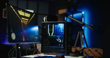 Masada kulaklıklar ve yüksek teknoloji VR kulaklığın yanında RGB 'nin yaktığı bilgisayarlı boş neon ışıklı oturma odası görüntüsü. Dairedeki bilgisayar çevresi ve bilgisayar ekranlarında açık bırakılan FPS video oyunu