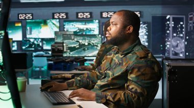 Officer doing tasks in military base, planning, analyzing and gathering information on enemy troops. Agent in base of operations doing assessment of enemy vulnerabilities, tracking, camera B clipart