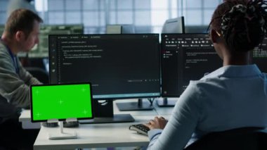 Bilgisayarlarda kod yazan ve ekipmanları güncelleyen bilişim destek çalışanları önünde izole edilmiş ekran tableti. PC masasındaki mühendisler sunucu kümelerini krom anahtar cihazı kullanarak denetliyor, kamera A