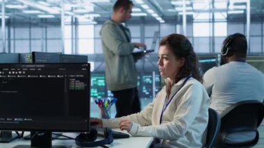 Yüksek teknoloji sunucu merkezinde çalışan iyimser bir bilgisayar bilimcisi muazzam miktarda veri işleme yeteneğine sahip. PC 'de gülümseyen kadın klavyede yazı yazıyor, sunucuları güncelliyor ağ kaynaklarını kontrol ediyor, kamera A