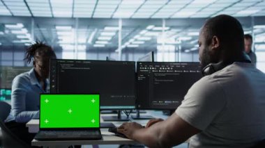 Kulaklıkla müzik dinlerken sunucu çiftliğinde programcının yanındaki izole ekran bilgisayarı. İşçi krom anahtar defteri, kamera B 'ye izinsiz erişime karşı donanımı koruyor