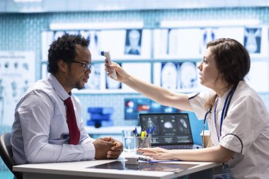 Sıhhiye uzmanı doğru teşhis ve semptomları bulmak için bir termometre kullanarak, tıbbi sigorta hizmetlerindeki hastaları desteklemek için modern sağlık uygulamaları sergiliyor. Ateş ölçümleri.