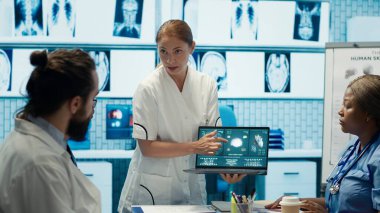 Çeşitli tıbbi ekipler test sonuçlarını inceliyor ve modern bir klinikte hasta bakımının kalitesini artırmak için yenilikçi tedavi planlarını tartışıyorlar. Doktorlar ve hemşireler röntgen taramalarını gözden geçirir. Kamera A.