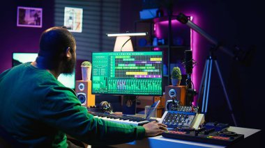 Yeni bir parça yaratmak için piyano elektronik klavye çalan ses düzenleyicisi, eski kayıtlardaki ses seviyelerini ayarlıyor. Müzik yapımcısı sesleri kaydediyor, Midi controller 'da melodiler çalıyor. Kamera B.