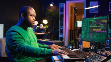 Erkek sanatçı ev stüdyosunda elektronik piyano klavyesinde müzik yapıyor. Ses mühendisi, akustik aletler ve teçhizatla MIDI kumandasını oynuyor, kayıt yapıyor ve bir film müziği besteliyor. Kamera B.