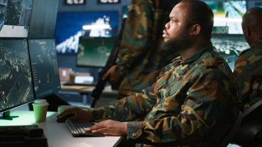 Komuta merkezindeki askeri asker ulusal güvenlik operasyonlarını denetliyor, telefonla konuşuyor. Afro-Amerikan ordu uzmanı izleme odasında, kamera A 'da telefon görüşmesi yapıyor.