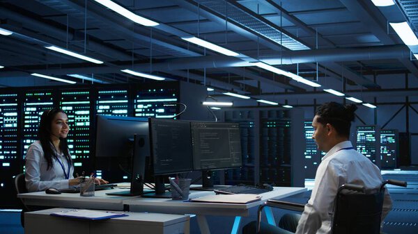 Person with disability in inclusive high tech server room facility ensuring data remains shielded from threats. Wheelchair user protecting data center hardware equipment, camera B
