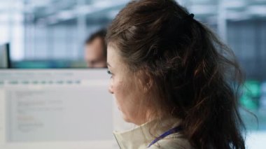 Veri merkezinde gülen bilişim mühendisi, pc kullanarak rackmount 'ları etkileyen yanlış yapılandırmaları buluyor. Sunucuları kontrol eden neşeli bir kadın dar geçitleri kontrol ederek yavaş veri aktarım oranlarına ve kameraya yol açıyor.