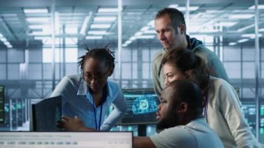 Sunucu merkezinde çalışan çok ırklı mühendisler veri analizi için bilgisayarları kullanıyor. Veri merkezindeki altyapıyı inceleyen çok ırklı bir grup çalışanın sistem bütünlüğü ve güvenliği sağlaması, kamera A