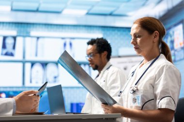 Klinikteki uzmanlardan oluşan tıbbi ekip test sonuçlarını ve masadaki radyografiyi inceliyor. Lisanslı sağlık görevlileri hastalık önleme, sağlık uzmanlığı ve takım çalışması için tedavi seçeneklerini tartıştılar.