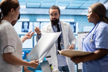 Röntgen taramasını inceleyen doktorlar yeni tedavi planları geliştirmek için çalışanlarla bir toplantı yapıyorlar. Doktorlar analitik ve tanı kontrolü ve sağlık sektörü için toplu iş yapıyorlar..