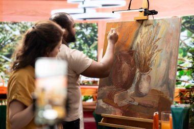 Ressamlardan oluşan bir ekip internet için bir sanat dersi kaydediyor, resim teknikleri ve sanat eserleri için ilham öğretiyorlar. Erkek ve kadın sanat stüdyosunda bir yaratılış üzerinde çalışıyor, motivasyon.