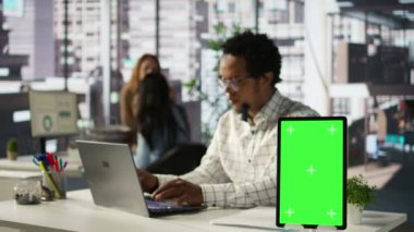 Finansal danışman masasındaki izole edilmiş fotokopi alanının yanında idari görevler yürütüyor, iş stratejisine odaklanıyor. Uzman performans beklentilerini aşmak için teknolojiyi kullanır. Kamera B.