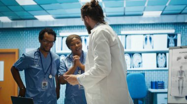 Neşeli, kendine güvenen doktorlar ve hemşireler teşhis için doğru tedavi planını buluyorlar. Yetenekli sağlık sektörü çalışanları. Sağlık personeli gülümseyip el çırpıyor. Dolapta iyi haberler var. Kamera B.