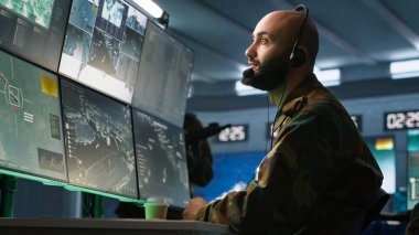 Askeri hareket memuru kulaklık mikrofonuyla ön saflarda savaşan piyade birliklerine bilgi veriyor. Askerler için istihbarat sağlayan ordu uzmanı, görev faaliyetlerini koordine eden, kamera A