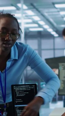 Veri merkezinde iş arkadaşıyla birlikte çalışan bir sistem yöneticisi farklı iş yükleri için hesaplama kaynakları sağlıyor. Yapay zeka süper bilgisayarlarını, kamera A 'yı izlerken iş arkadaşıyla konuşan bilişim uzmanı.