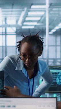 Sunucu merkezinde çalışan çok ırklı mühendisler veri analizi için bilgisayarları kullanıyor. Veri merkezindeki altyapıyı inceleyen çok ırklı bir grup çalışanın sistem bütünlüğü ve güvenliği sağlaması, kamera A