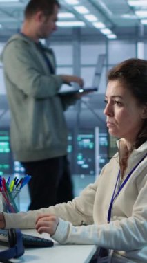 Yüksek teknoloji sunucu merkezinde çalışan iyimser bir bilgisayar bilimcisi muazzam miktarda veri işleme yeteneğine sahip. PC 'de gülümseyen kadın klavyede yazı yazıyor, sunucuları güncelliyor ağ kaynaklarını kontrol ediyor, kamera A