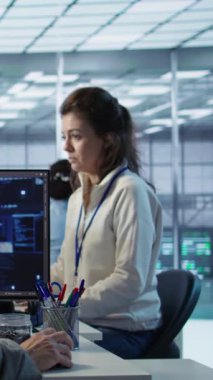 Yapay zeka video yazılımı üretirken sunucu odasında iş arkadaşıyla sohbet eden bir mühendis. BT çalışanı ve iş arkadaşı konuşarak yapay zeka yayılımı uygulaması, kamera B