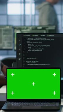 Sunucu merkezindeki çeşitli geliştiriciler yeşil ekran laptopunu kullanarak yanlış yapılandırmaları arıyorlar. Afrika kökenli Amerikalı bilişim uzmanları veri merkezindeki hataları kroma anahtar not defteri, kamera A ile onarıyor.