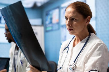 Çeşitli tıbbi ekipler röntgen sonuçlarını ve sağlık kayıtlarını incelemek için kabinede toplanıyor. Lisanslı doktorlar ve hemşireler uygun tedavi planlarını geliştirmek ve uzmanlıklarını göstermek için birlikte çalışıyorlar..