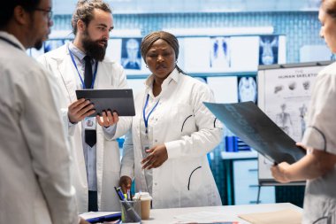 Sağlık ekibi röntgen sonuçlarını inceler ve tıbbi personel ve tedavi seçenekleriyle yapılan bir toplantıda hastalıkların önlenmesini tartışır. Radyoloji uzmanları teşhis taramalarını inceliyor.